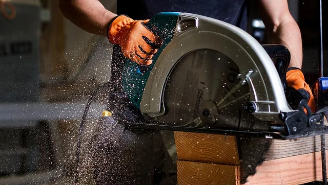 Håndverker kapper trevirke med sirkelsag, sagflis spruter i verkstedmiljø