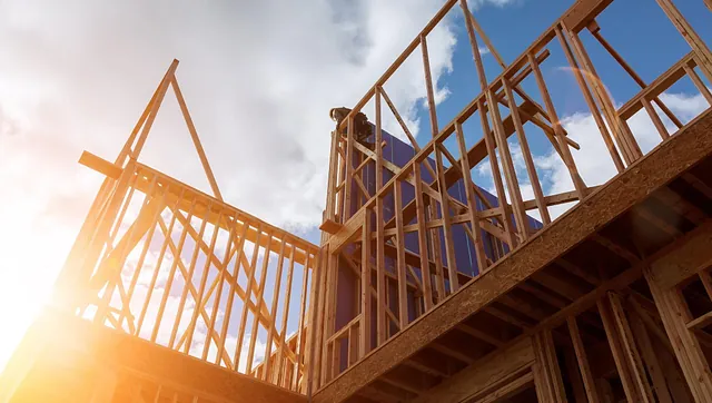 Tømrer monterer reisverk på enebolig under oppføring i sollys